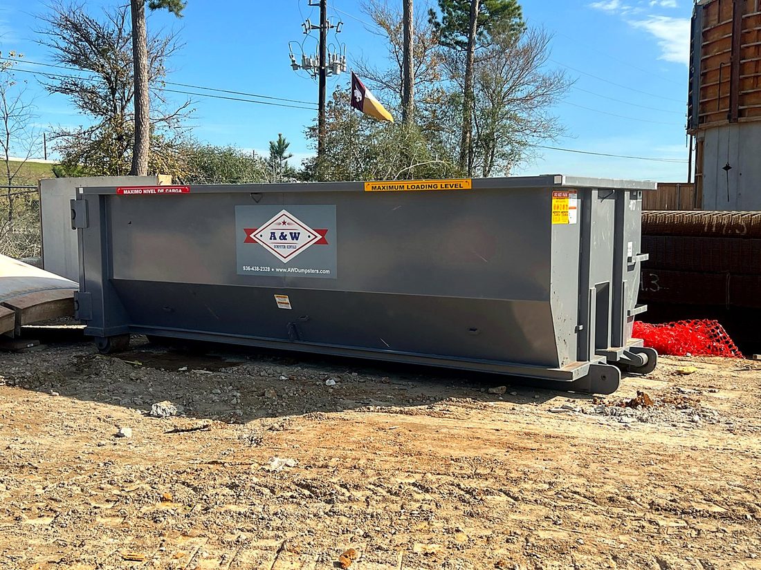 A&W roll-off dumpster on a wooded construction lot near Montgomery