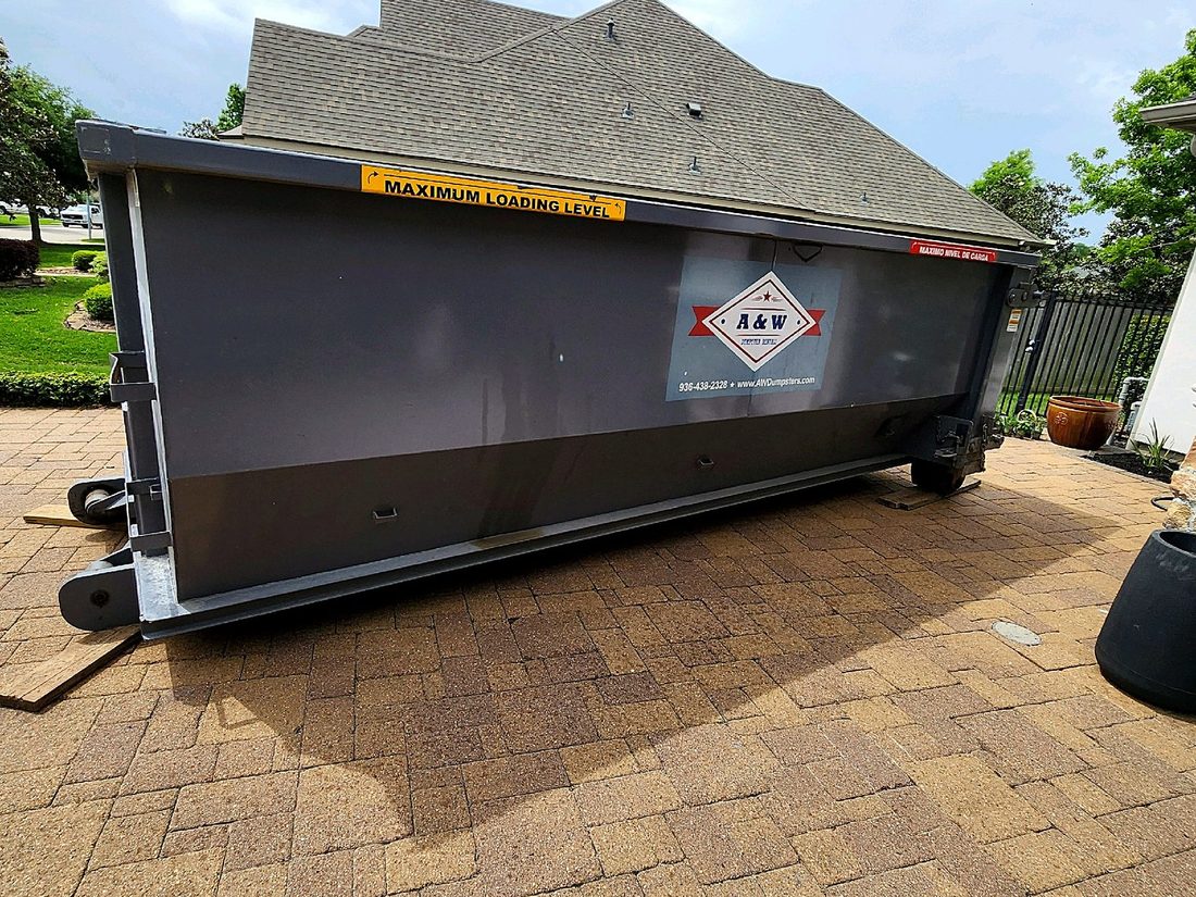 A&W roll-off dumpster on a paver patio during a home remodel