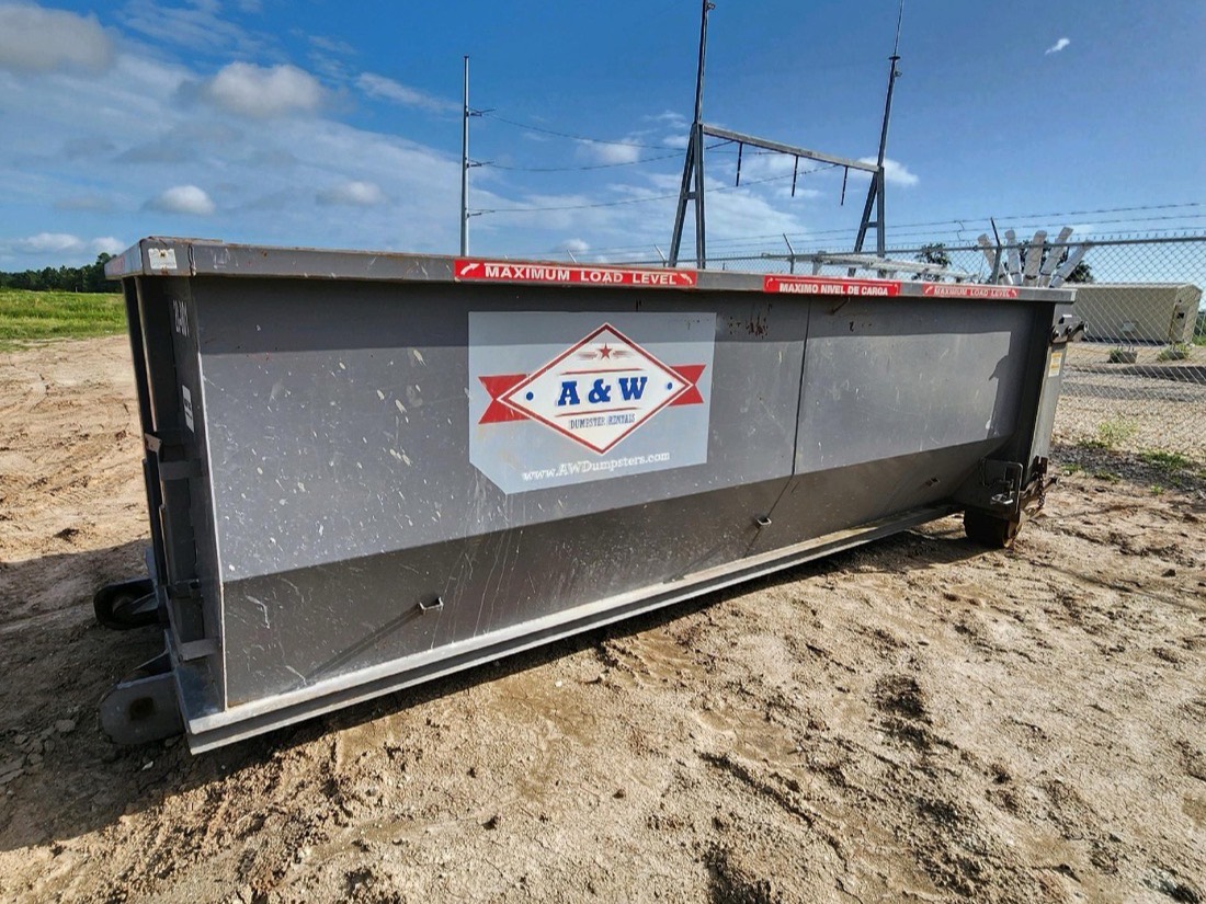 A&W branded roll-off dumpster at the yard under a blue Texas sky